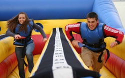 A boy and a teenage girl running hard on a bungee run course in McDonough, GA
