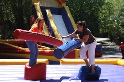 Two adults having fun while standing on top of inflatable joust pods at a fraternity in Atlanta, Georgia